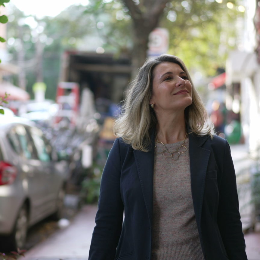 A contemplative middle age woman walking in city street. Pensive mature 50s person daydreaming outside in urban sidewalk in daylight